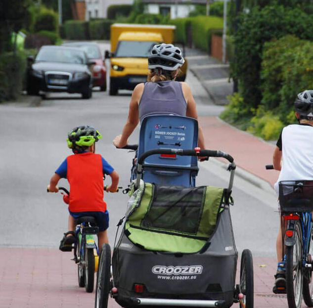 Familie auf dem Rad: Mutter mit Fahrradanhänger und drei radfahrenden Kindern