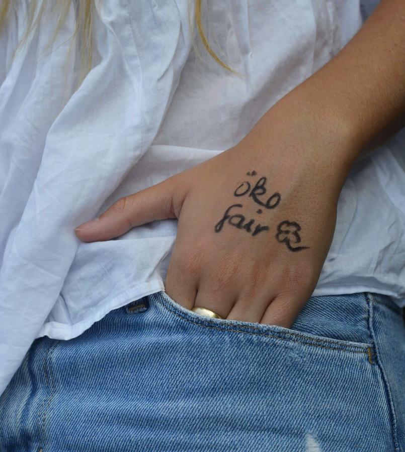 Hand mit Schriftzug "öko fair" in eine Jeanshosentasche gesteckt